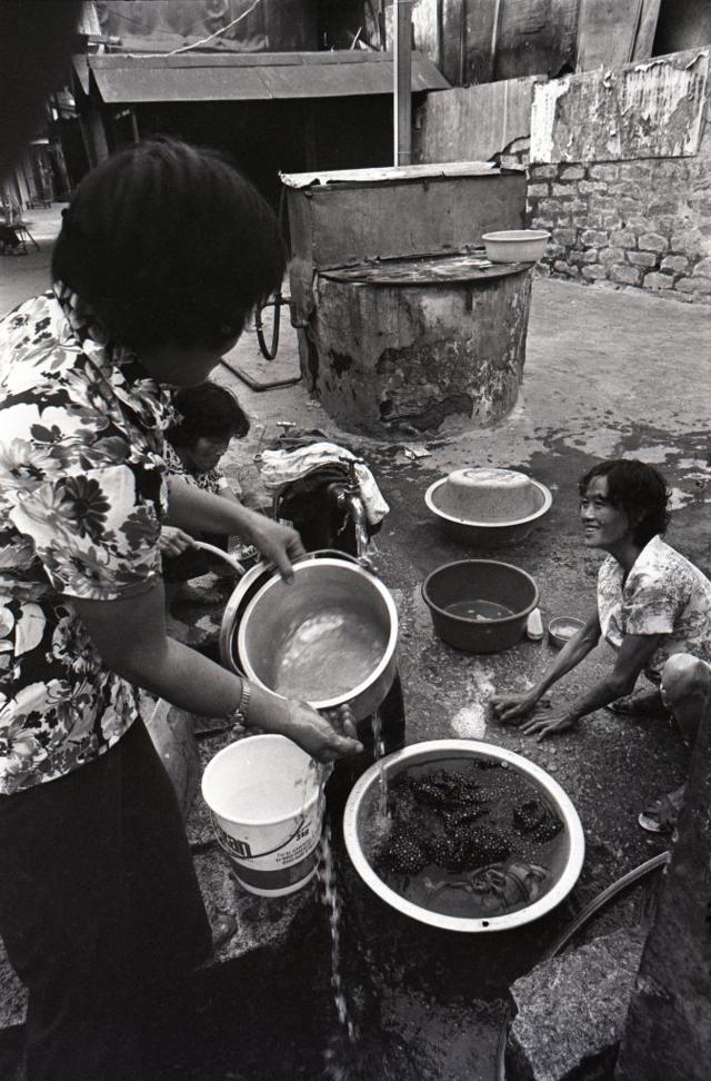 Mulheres lavando panelas na rua.