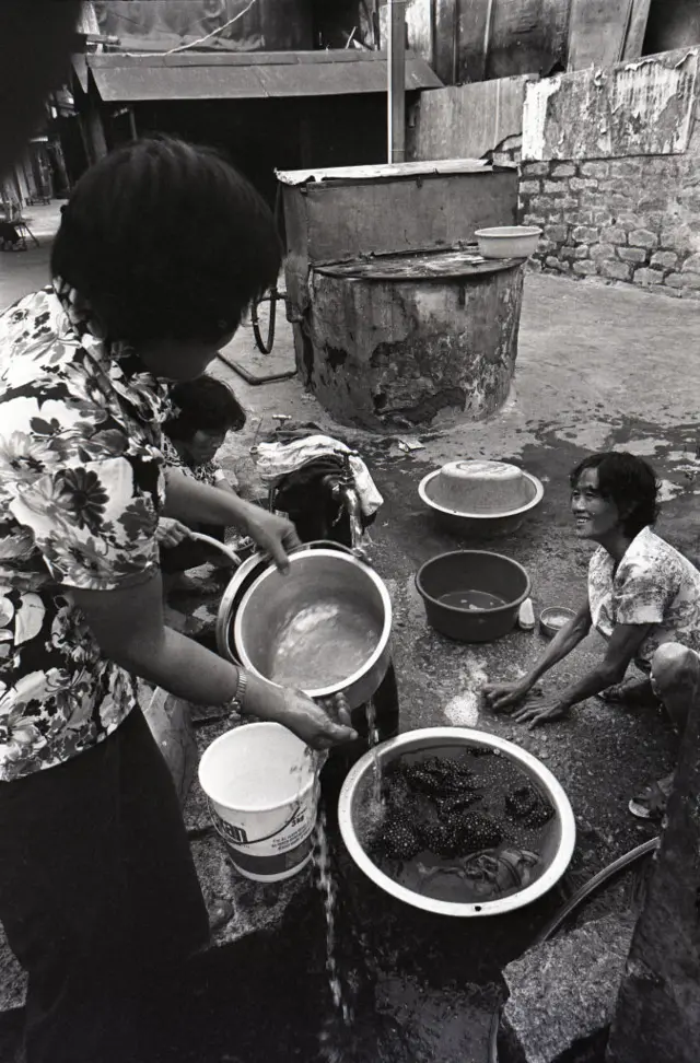 Mulheres lavando panelas na rua.