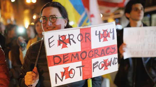 Девушка с плакатом на акции протеста в Тбилиси. 21 февраля 2026 года