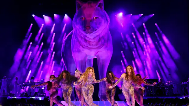 Shakira dan para penarinya melakukan gerakan tari saat tampil di bawah patung serigala betina raksasa