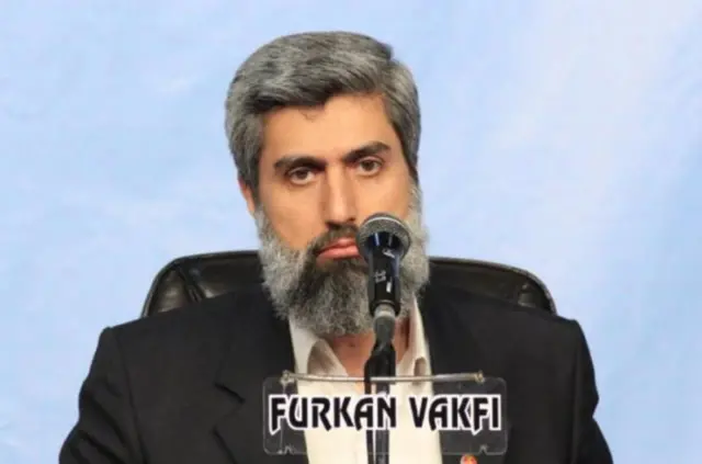 Alparslan Kuytul, üstünde Furkan Vakfı yazan bir mikrofonla konuşurken