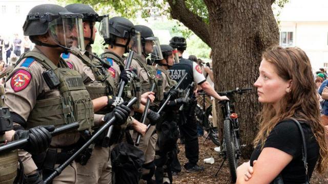 Una estudiante mira fijamente a una hilera de policías estatales de Texas durante las protestas. 