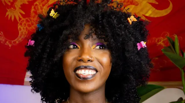 Gros plan sur la YouTubeur Muthoni Gitau avec des papillons dans les cheveux.