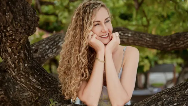 Amy Minkley bir ağacın önünde gülümsüyor. 