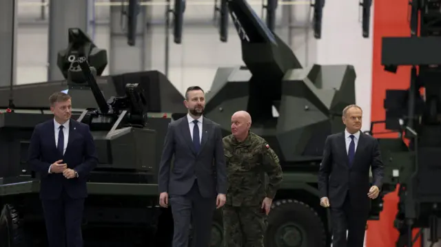 Premier Polski Donald Tusk oraz wicepremier i minister obrony Władysław Kosiniak‑Kamysz idą przed systemami przeciwlotniczymi zdolnymi do zwalczania bezzałogowych statków powietrznych, zaprezentowanymi w Kobyłce