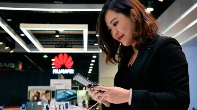 mulher olha telefone da Huawei