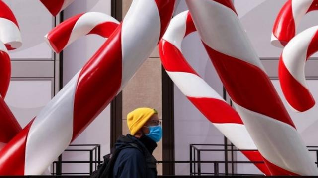 Person in face mask amid candy canes on 6th Avenue in New York