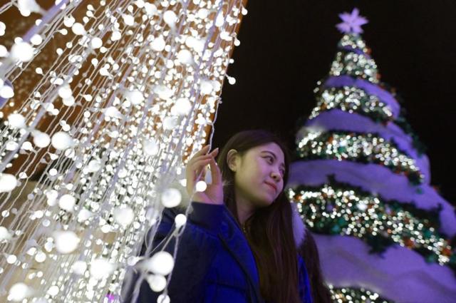 2018年12月22日，北京一名女士在圣诞树旁自拍。
