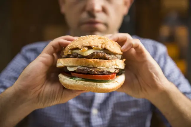 Homem comendo hambúrguer