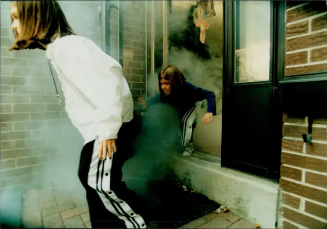 두 소녀가 화재 대피 훈련 중 연기가 자욱한 벽돌 건물에서 빠져나오고 있다