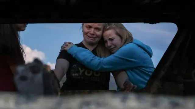 Miembros de la familia LeBarón ante uno de los vehículos quemados tras la emboscada.