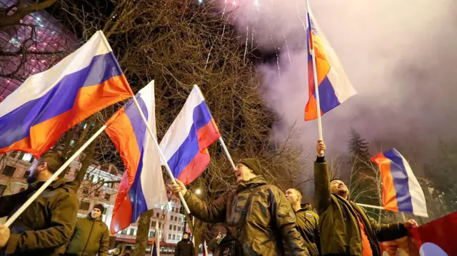 Pro-Russia activists don wave flags as dem dey celebrate for di streets wit fireworks inside di sky for di square at Donetsk, Ukraine on 21 February 2022.