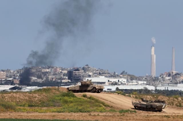 دخان يتصاعد من قطاع غزة بينما تناور الدبابات الإسرائيلية بالقرب من السياج الحدودي، كما يظهر من مكان غير معلوم في جنوب إسرائيل