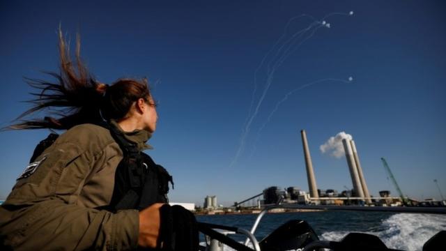 Uma soldado israelense observa enquanto o sistema anti-míssil de Israel, o Domo de Ferro, intercepta foguetes lançados da Faixa de Gaza