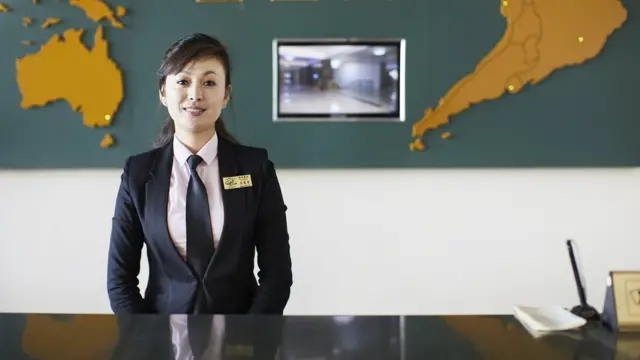 Recepcionista no hotel Changgwangsan atende os clientes