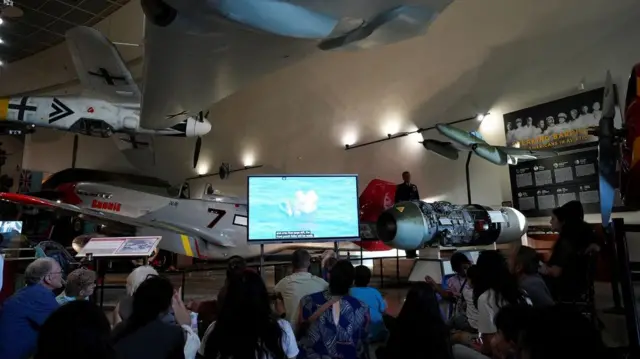 Desetine ljudi gleda u televizor iščekujući sletanje posade Artemis Dva