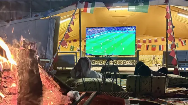 Qataríes viendo el partido delante de la fogata que atempera la noche fresca.