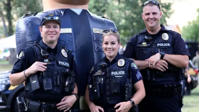 Doi polițiști și o polițistă, în uniformă, pozează pentru o fotografie într‑un parc local din orașul Golden, Colorado.