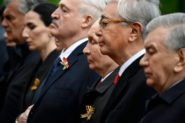 Vista lateral de Vladímir Putin de pie en fila junto a otros líderes extranjeros, entre ellos Alexander Lukashenko, de Bielorrusia.