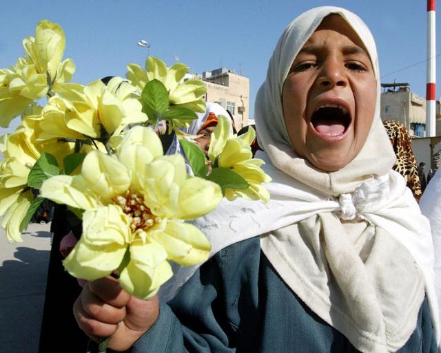 طفلة عراقية تحمل وروداً صفراء