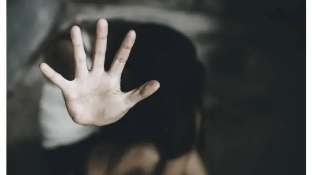 امرأة ترفع كفها بإشارة كفى