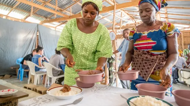 Deux femmes servent de la nourriture dans des assiettes, à Ganta, au Liberia.