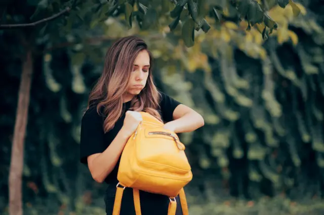 Una mujer busca algo que ha perdido en su bolso