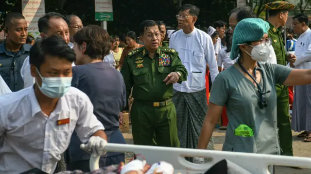 Le chef militaire du Myanmar, Min Aung Hlaing (C), fait un geste alors que les survivants du tremblement de terre se rassemblent dans l'enceinte d'un hôpital à Naypyidaw, le 28 mars 2025