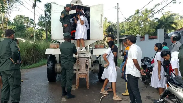 යුද හමුදා රථයකින් පිටතට බසින පාසල් සිසුන් 