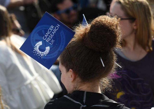 Mulher segura bandeirajogo among usorganização que pesquisa câncer