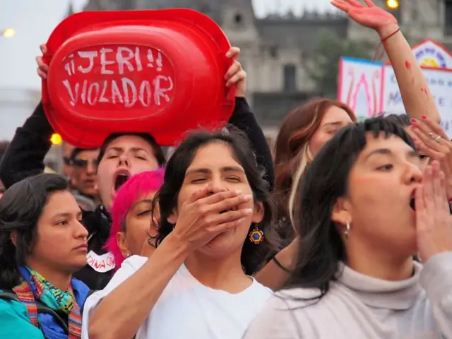 "Jeri violador" puede leerse en el fondo de una pequeña bañera de color rojo. La sostiene una mujer que tiene la boca abierta, gritando. Hay a su alrededor más mujeres que protestan. 