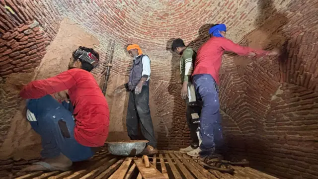 Four men put the mortar on walls of the royal kitchen - which has sandstone bricks visible - as part of the restoration. 
