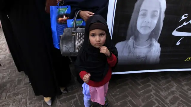 девочка на фоне плаката с фото Зейнаб