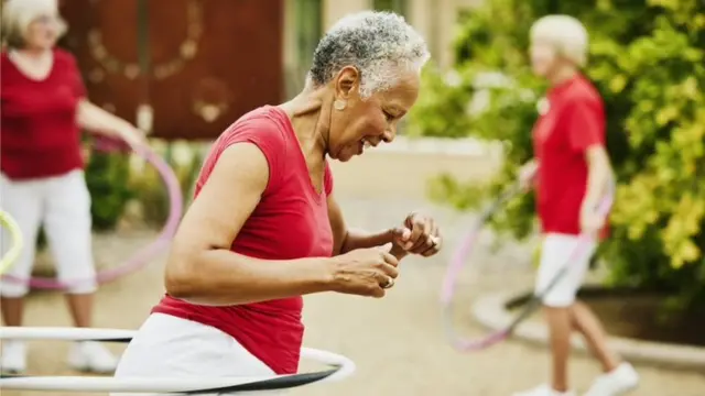 Uma mulher negra idosa se exercitando com um bambolê