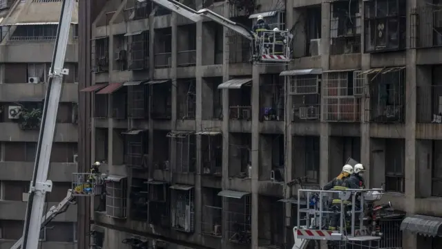 Firefighters search for victims from a residential building in the wake of a fire on 14 October 2021, in Kaohsiung, Taiwan
