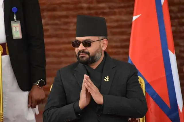 तस्बिरमा कालो कोट लगाएर नमस्ते गरिरहेको अवस्थामा प्रधानमन्त्री बालेन्द्र शाह।