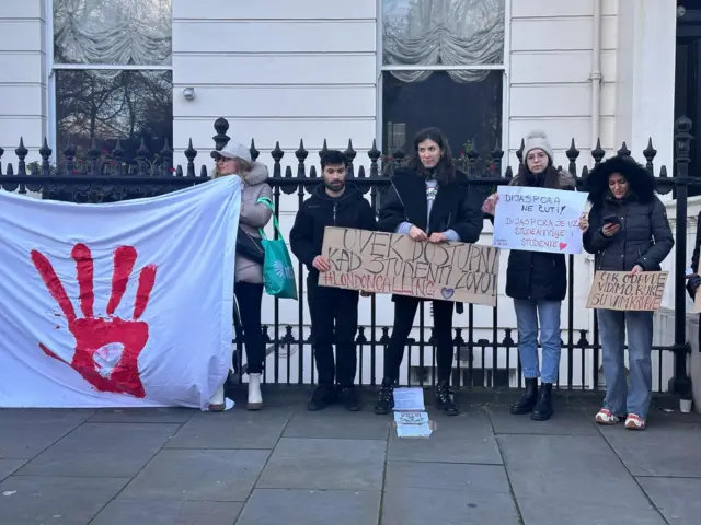 Ljudi drže transparent ispred Ambasade Srbije u Londonu