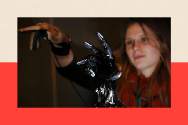 На переднем плане роботизированная черная рука, на заднем плане девушка с вытянутой рукой в перчатке, от которой вниз отходит провод.