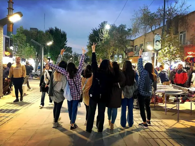 چند دختر بدون حجاب در خیابانی در ایران دستانشان را به علامت پیروزی بالا گرفته‌اند