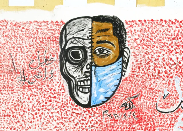 Wani zane a bango dake nuna rabin fuska dauke da takunkumi da kuma kokon kai da babu takunkumin, a Khartoum dake Sudan ranar Laraba 8 ga watan Afrilu 2020.
