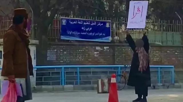 Adela brandissant sa pancarte.