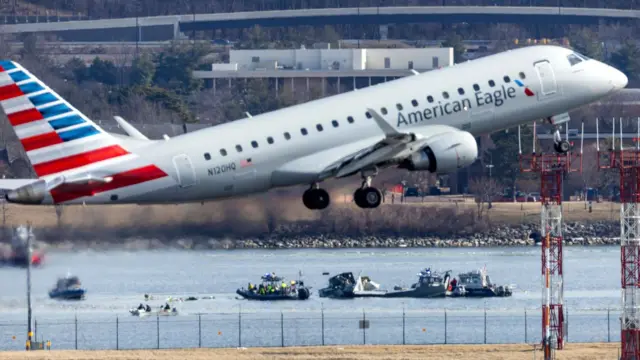 Um voo da American Eagle decola do Aeroporto Nacional Ronald Reagan de Washington em frente aos destroços de um avião comercial que colidiu com um helicóptero militar