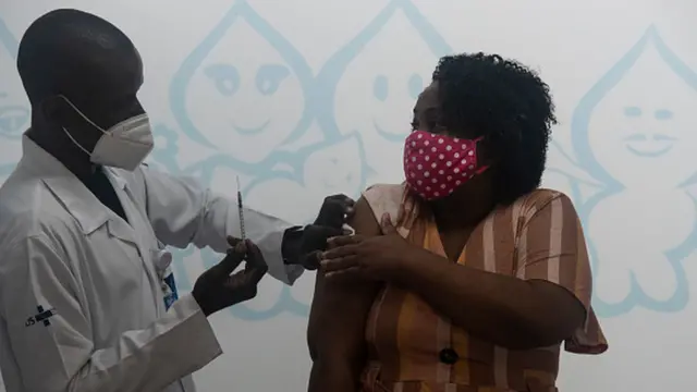 Enfermeiro aplica vacina contra a covid-19 no braço de uma mulher
