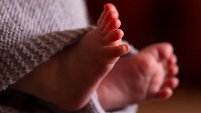 A imagem mostra dois pés de um bebê ainda bem pequeno