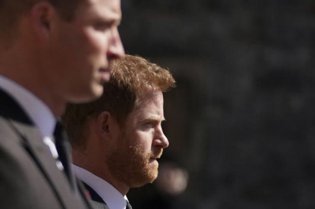 Fotografia colorida mostra dois homens jovens e brancostapajós betterno e feição séria; um deles é calvo e o outro é ruivo e usa barba
