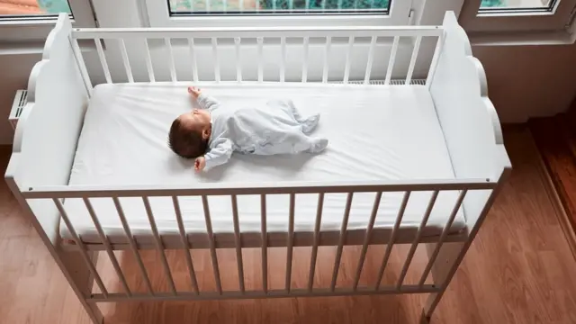 Bebé durmiendo solo en una cuna en una habitación.