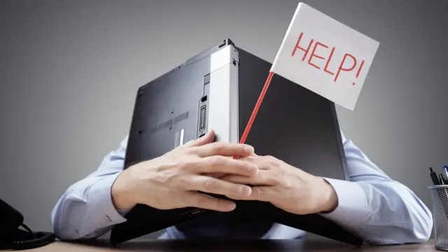 Un hombre estresado bajo una laptop pide ayuda