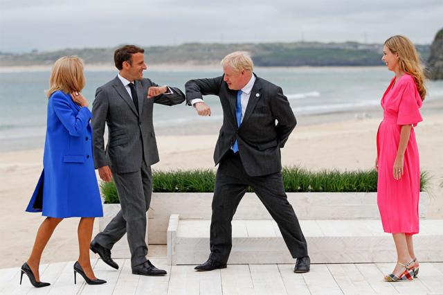 英國首相約翰遜與法國總統馬克龍行疫情下的"碰肘禮"，相互致意，他們的夫人凱莉·約翰遜（右）和布麗吉特·馬克龍（左）在一旁看著。全球冠狀病毒疫苗接種和氣候變化將成為七國領導人峰會的重點。