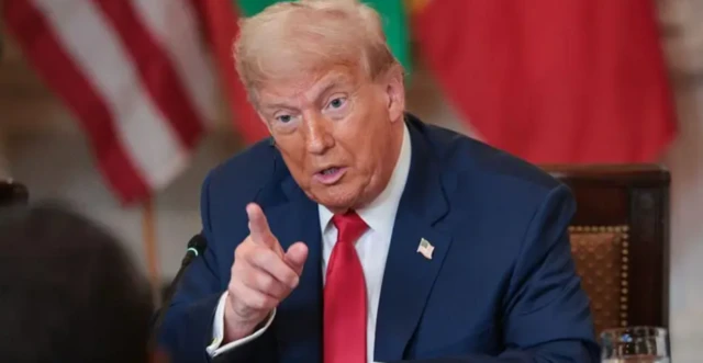 Donald Trump usando terno azul marinho e gravata vermelha e apontando o dedo indicador enquanto fala