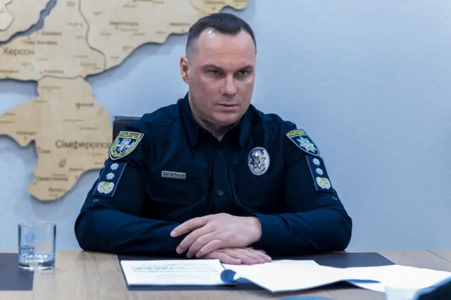 На фото Іван Вигівський, начальник Нацполіції, сидить з паперами за столом